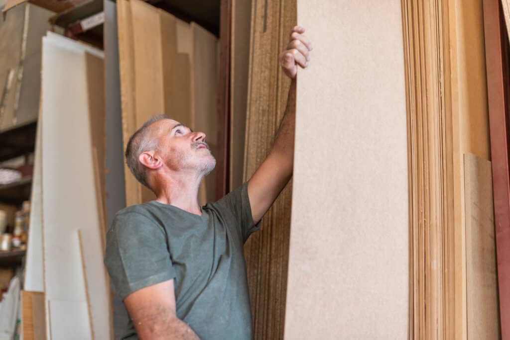 Worker man selecting a long MDF plank along others boards